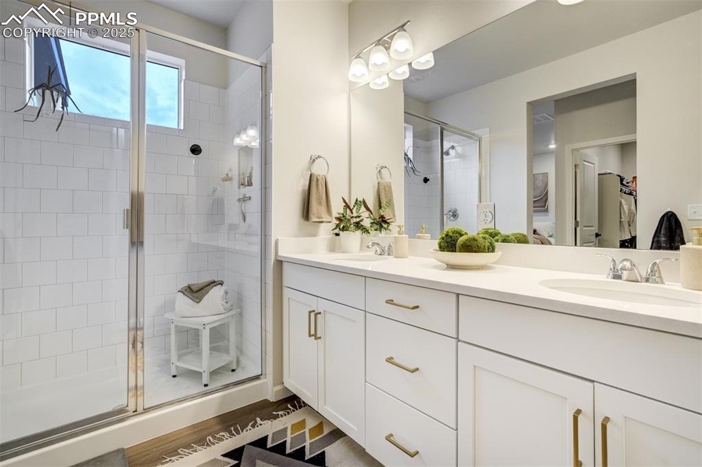 Image 23 of 50: Full bathroom featuring double vanity, a shower stall, and light wood finis