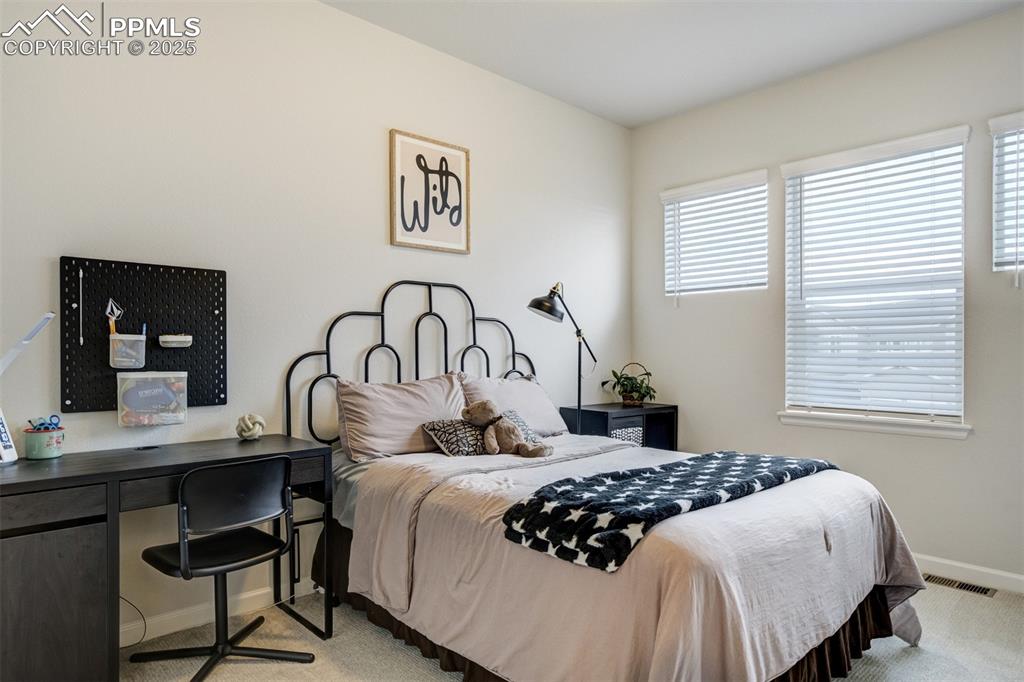 Image 28 of 50: Bedroom with light carpet and a desk
