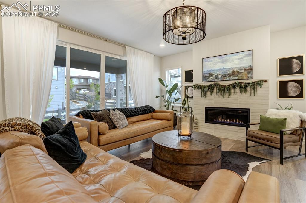 Image 3 of 50: Living area featuring light wood-style floors, a warm lit fireplace, recess