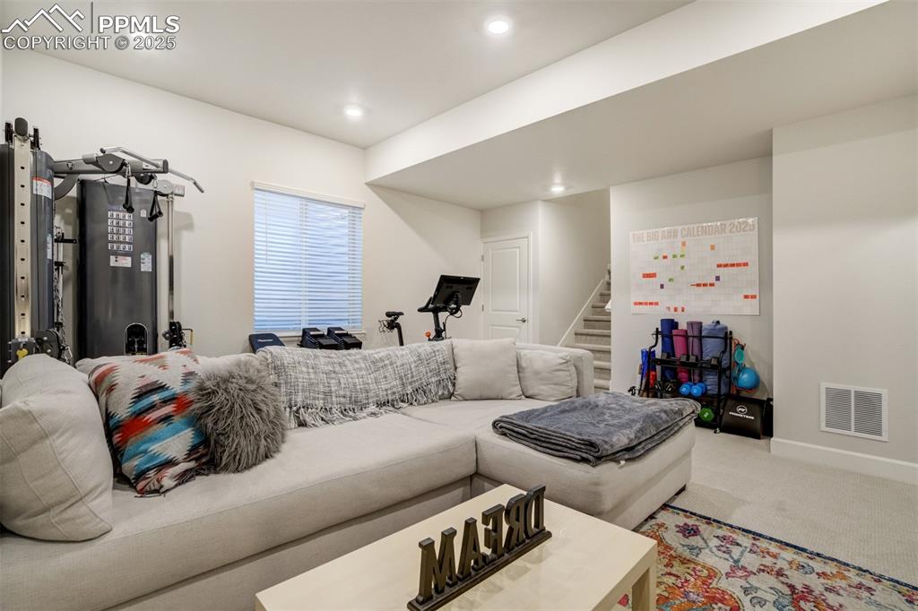 Image 34 of 50: Carpeted living area with stairs and recessed lighting