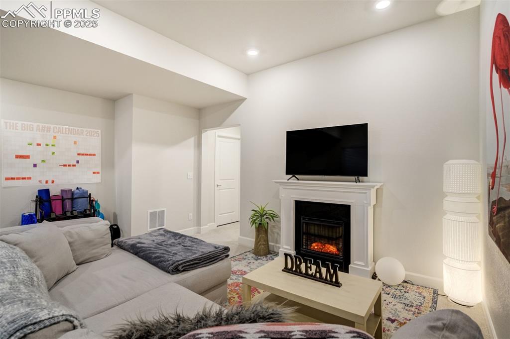 Image 36 of 50: Living area featuring a warm lit fireplace and recessed lighting