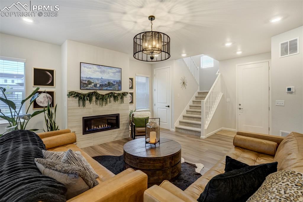 Image 4 of 50: Living room with light wood finished floors, stairs, a tile fireplace, rece