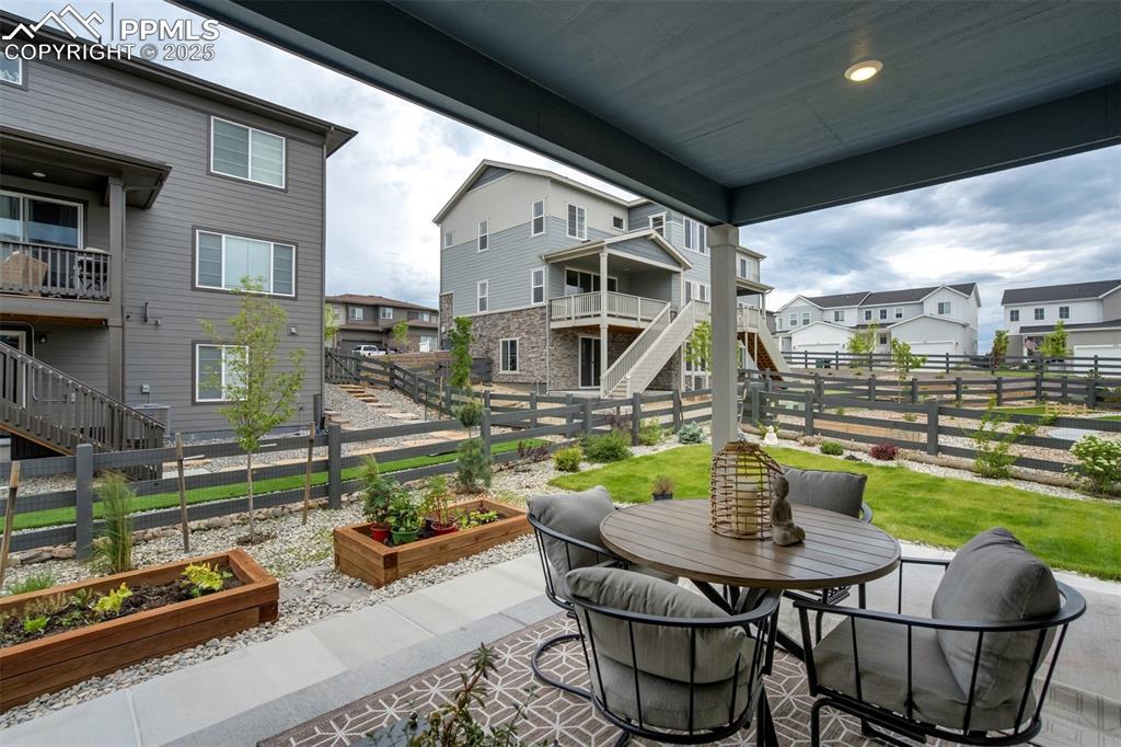 Image 40 of 50: Fenced backyard with a covered patio, raised garden beds, and outdoor dinin