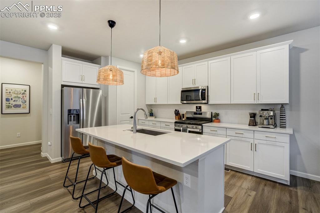 Image 8 of 50: Kitchen with appliances with stainless steel finishes, wood-type flooring, 