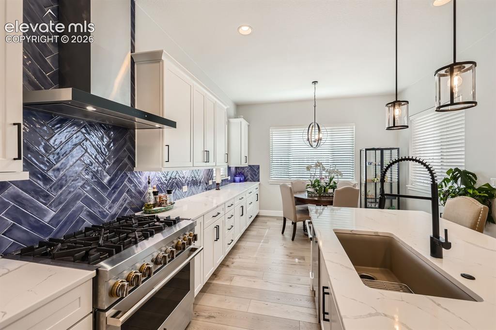 Image 13 of 38: Close up of the commercial range/oven.  Granite sink.