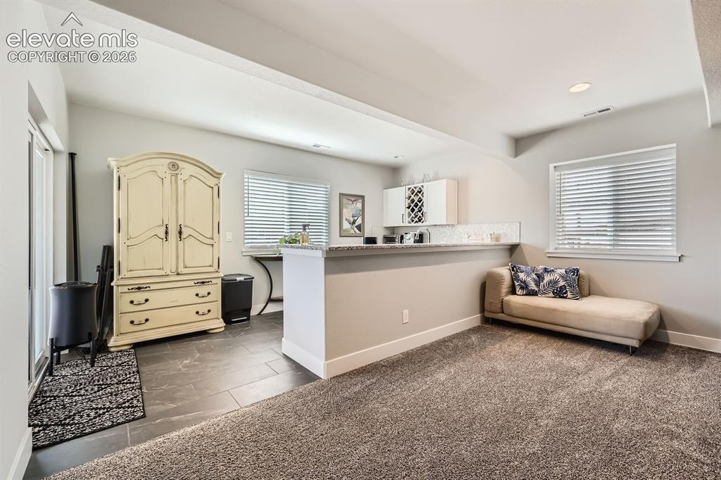 Image 25 of 38: Wet bar with a walk out to the covered backyard patio.