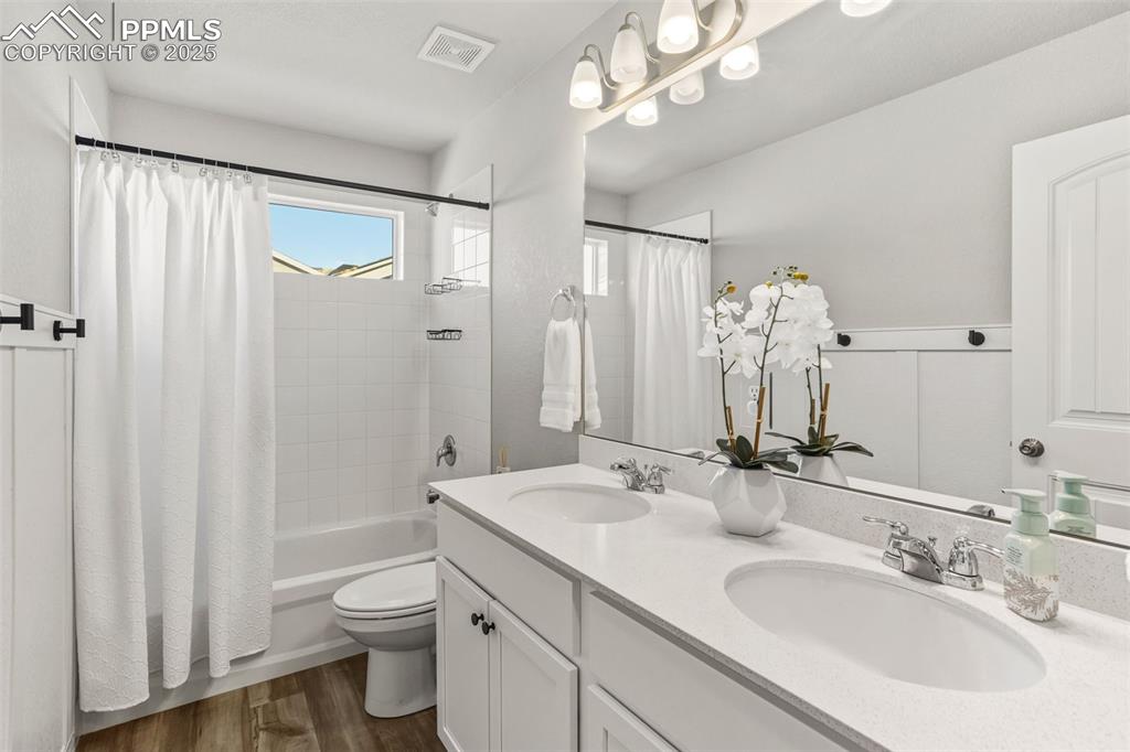 Image 24 of 37: Full bathroom with double vanity, shower / bath combo, and dark wood-style