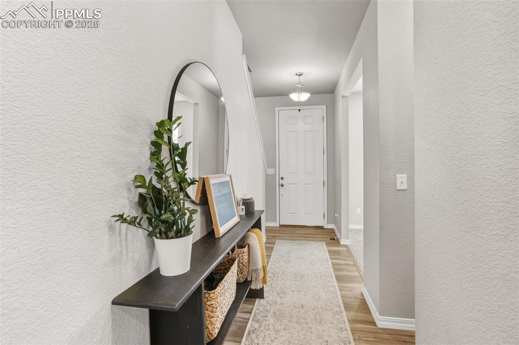 Image 6 of 37: Doorway with a textured wall and wood finished floors