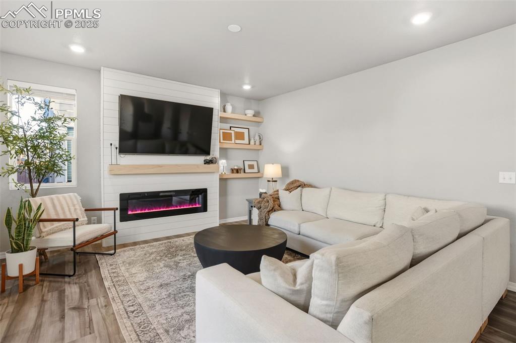 Image 9 of 37: Living area with recessed lighting, wood finished floors, and a large firep