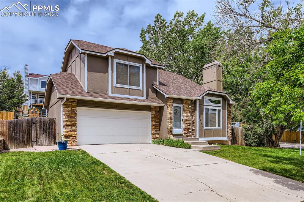 Caption: View of front of house featuring stone siding, an attached garage, a shingled roof, driveway, and a 