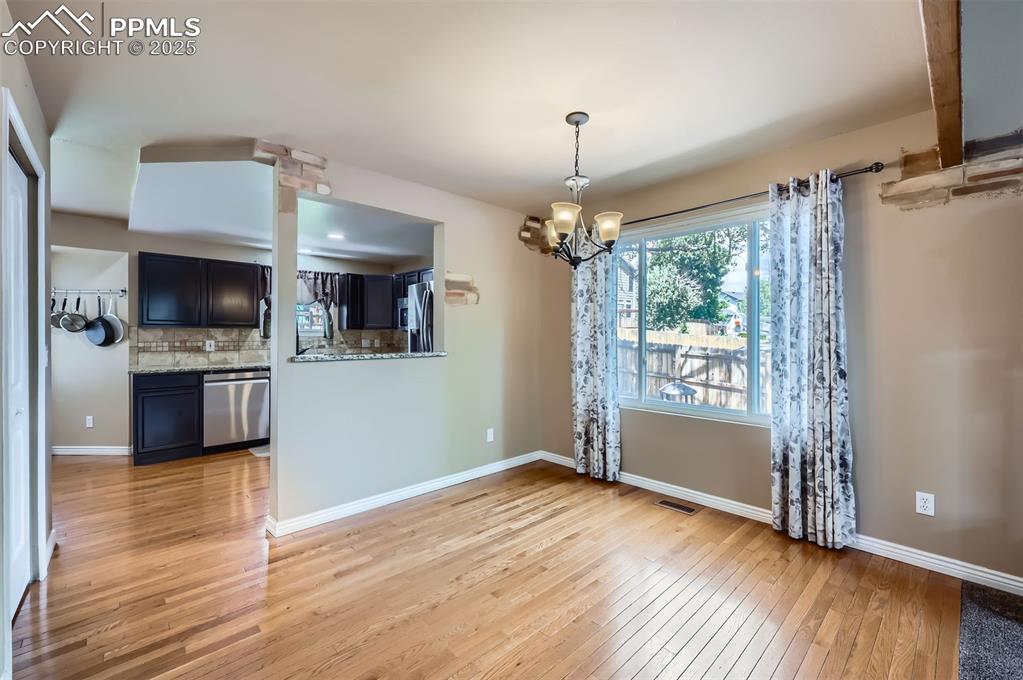 Image 11 of 28: Unfurnished dining area featuring light wood finished floors and a chandeli