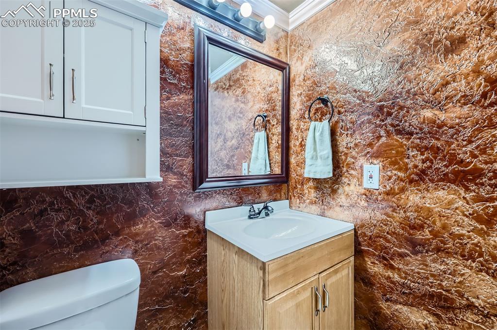 Image 12 of 28: Half bath featuring vanity and crown molding