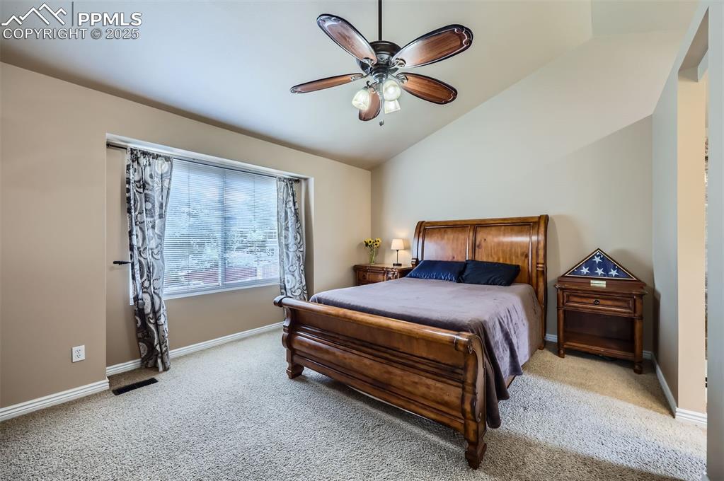 Image 13 of 28: Bedroom featuring light carpet, vaulted ceiling, and a ceiling fan
