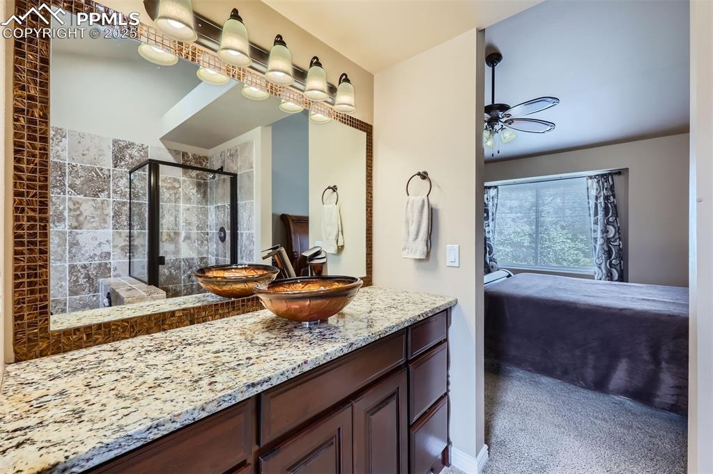 Image 16 of 28: Ensuite bathroom with vanity, a ceiling fan, and a Travertine tile shower