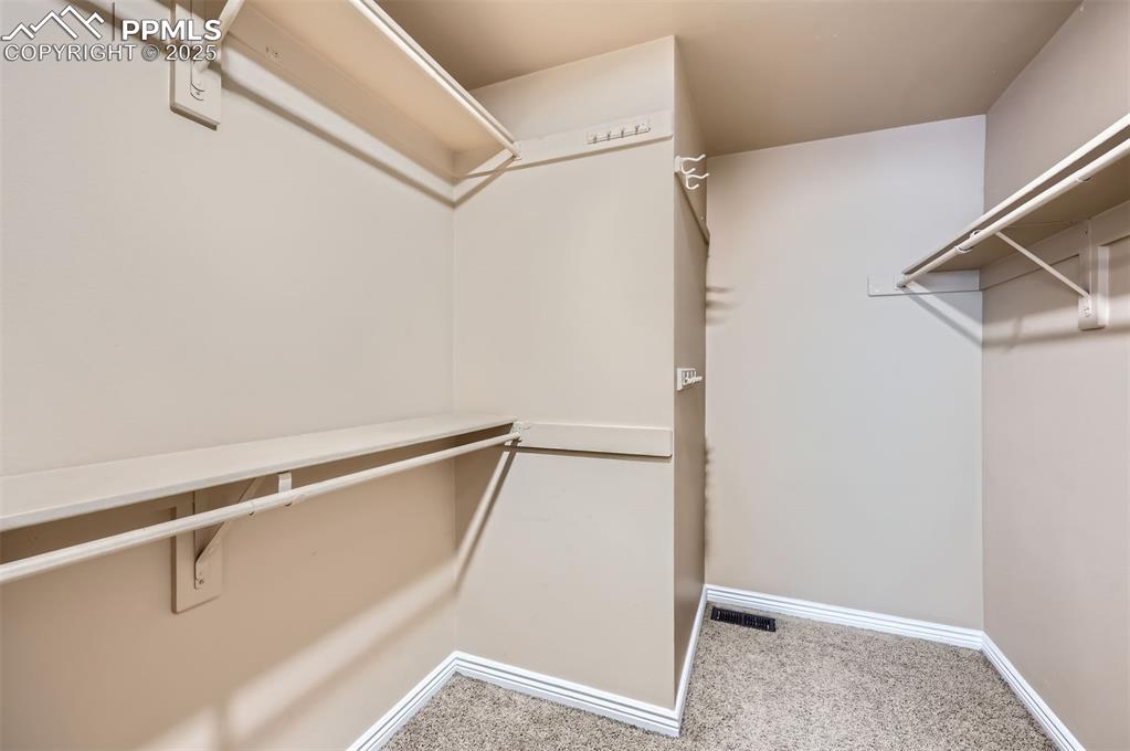 Image 17 of 28: Spacious master closet with carpet flooring