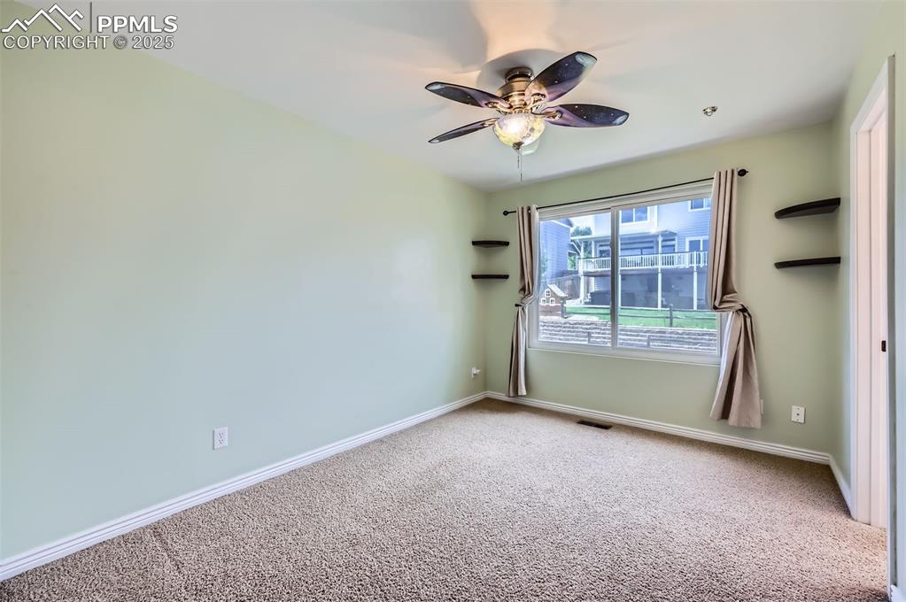 Image 18 of 28: Carpeted ensuite bedroom with ceiling fan and baseboards with connected Jac