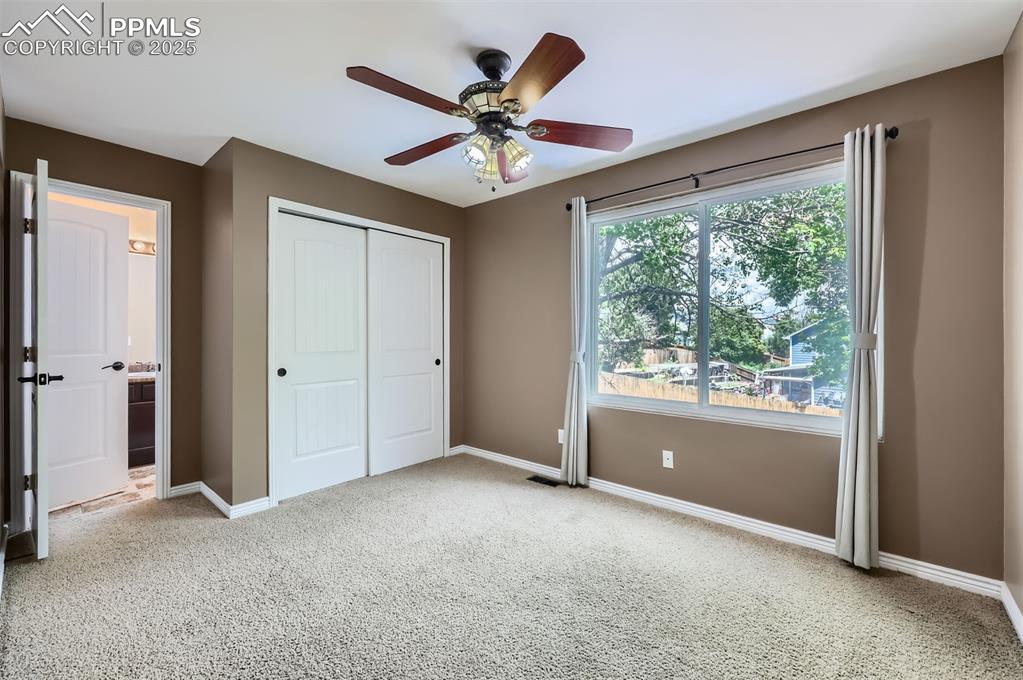 Image 19 of 28: Carpeted ensuite bedroom with a closet, carpet, ceiling fan, and connected