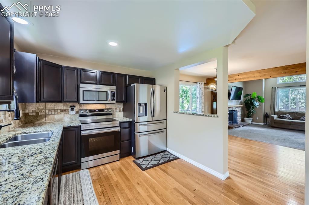 Image 7 of 28: Kitchen featuring some stainless steel smart appliances, backsplash, light