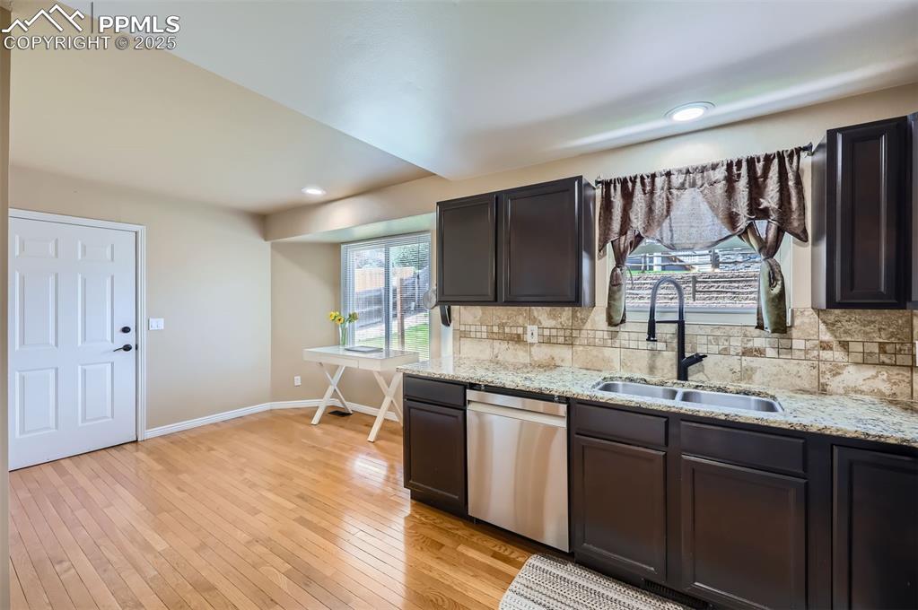 Image 8 of 28: Kitchen with dishwasher, tasteful backsplash, light wood flooring, light gr