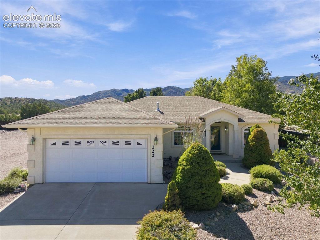 Image 1 of 36: Stucco exterior with an arched entryway, attached two-car garage, pitched s