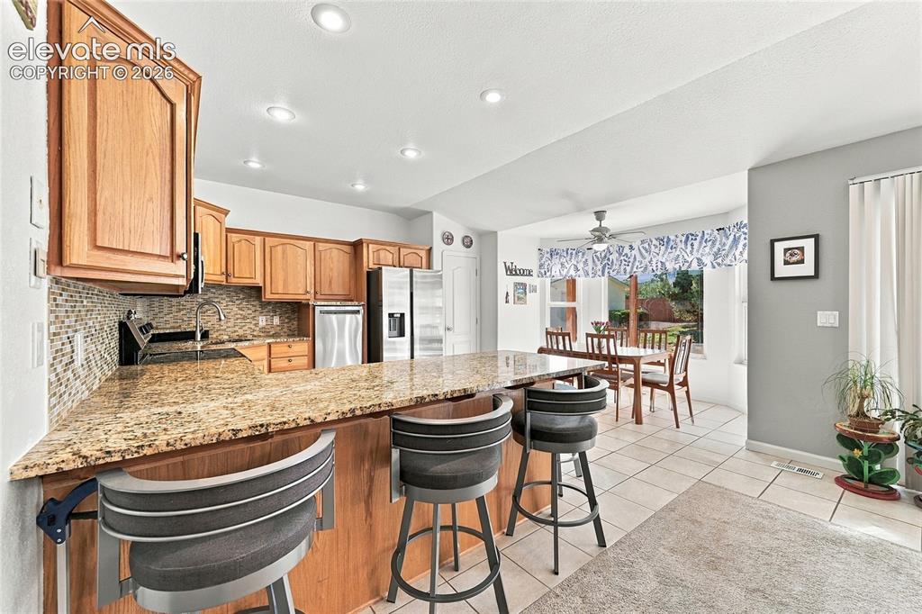 Image 11 of 36: Kitchen featuring wood cabinetry, stainless steel appliances, a mosaic tile