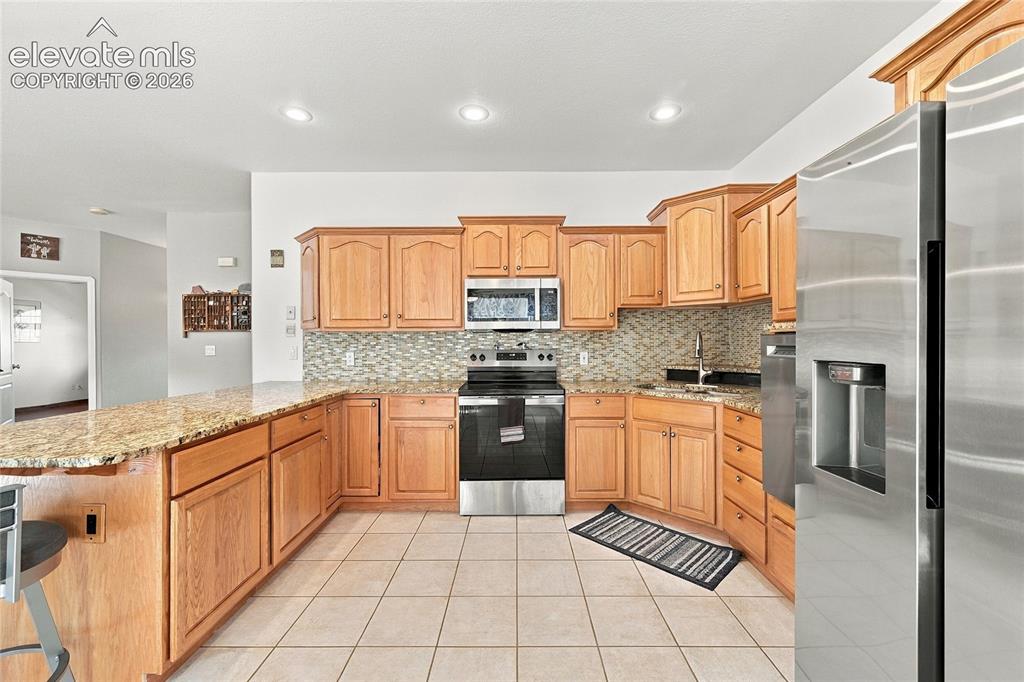 Image 13 of 36: Kitchen featuring wood cabinetry, granite countertops, tile flooring, stain