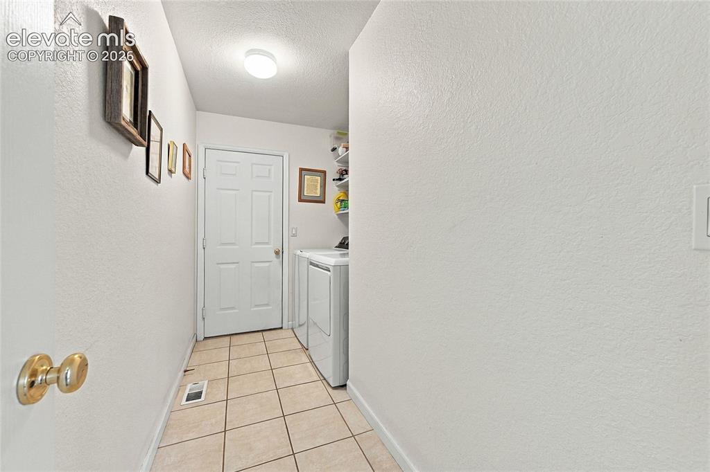 Image 22 of 36: Tile flooring, paneled door, flush-mount ceiling light, and built-in shelvi