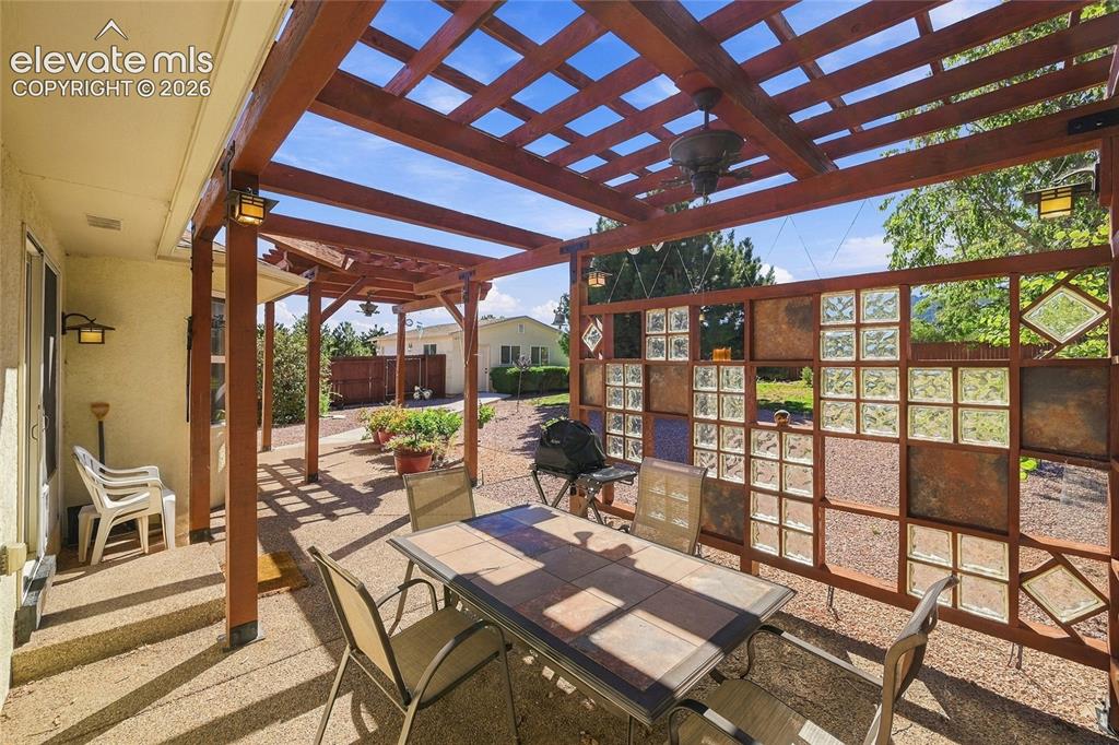 Image 23 of 36: Expansive patio featuring a wood pergola, integrated ceiling fan, and decor