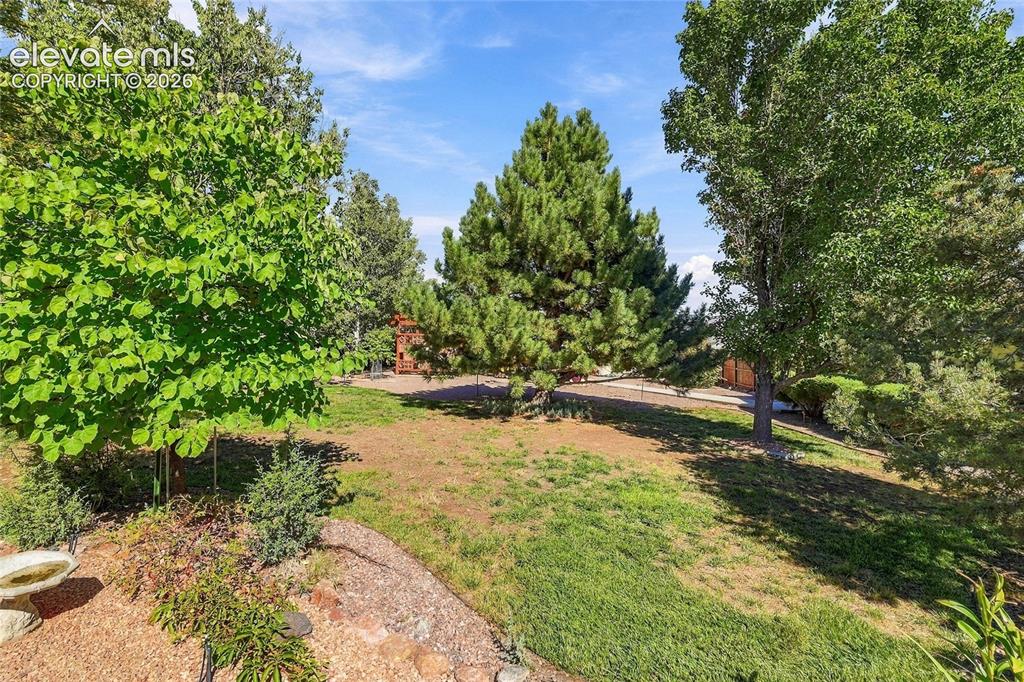 Image 26 of 34: Expansive yard featuring mature trees, established landscaping, and views