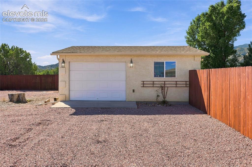 Image 27 of 36: Detached stucco garage/workshop with side door.  Heated with concrete floor