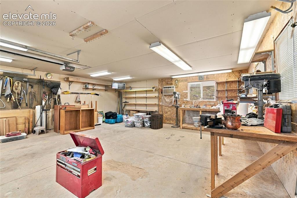 Image 30 of 36: Expansive garage/workshop space featuring concrete flooring, heater, wall a