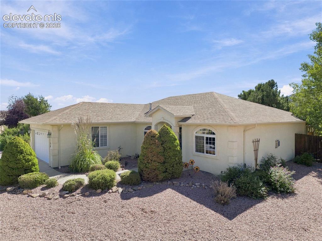 Image 32 of 36: Stucco exterior with a hip roof, arched window detail, and attached garage