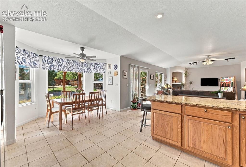 Image 8 of 36: Open concept kitchen and living area featuring tile flooring, a kitchen isl
