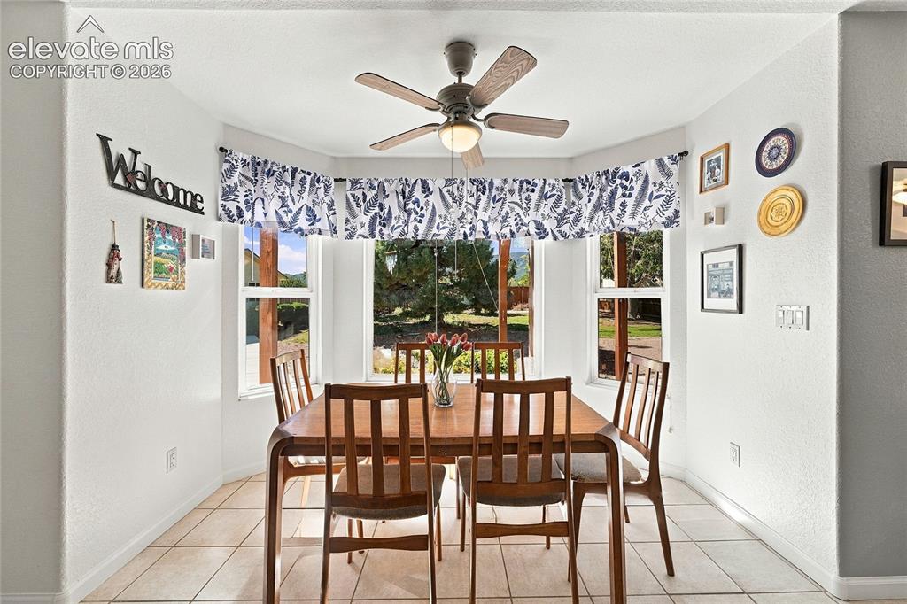 Image 9 of 36: Bay window featuring multiple panels, a ceiling fan with light, and tile fl