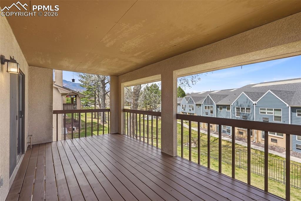 Image 12 of 44: Covered outdoor deck with wood flooring and dark wood railings, offering vi