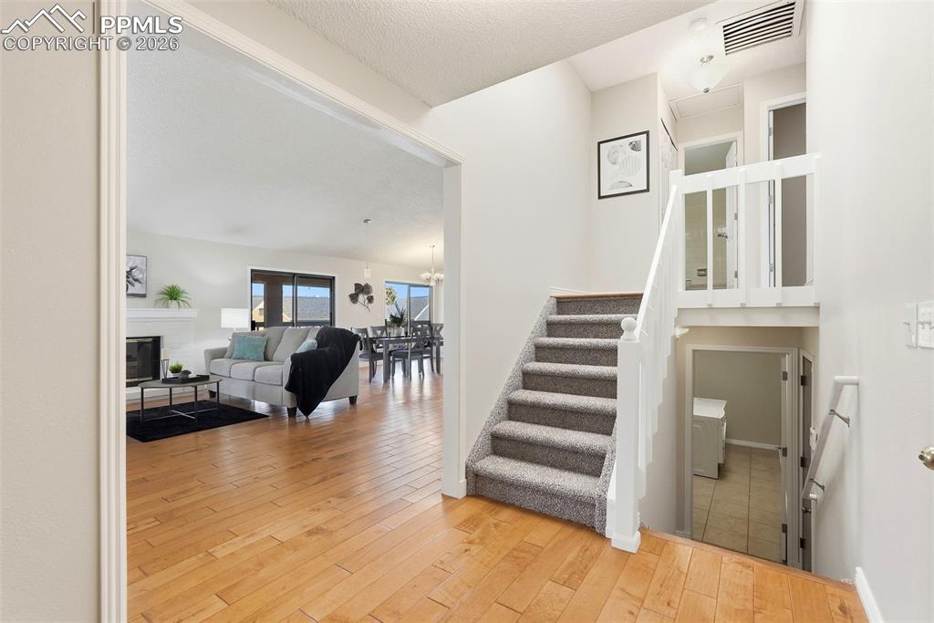 Image 13 of 44: Inviting entry with hardwood flooring and a carpeted staircase