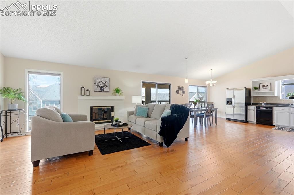 Image 14 of 44: This bright interior features hardwood flooring, a white fireplace, and vau