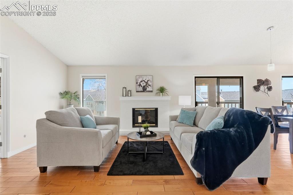 Image 15 of 44: Living room featuring hardwood floors, a white fireplace with a mantel, and