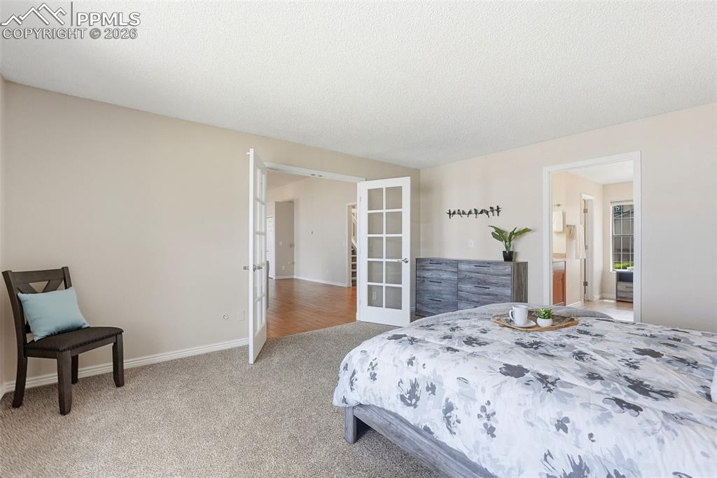 Image 18 of 44: The property features white french doors, neutral colored walls, and carpet
