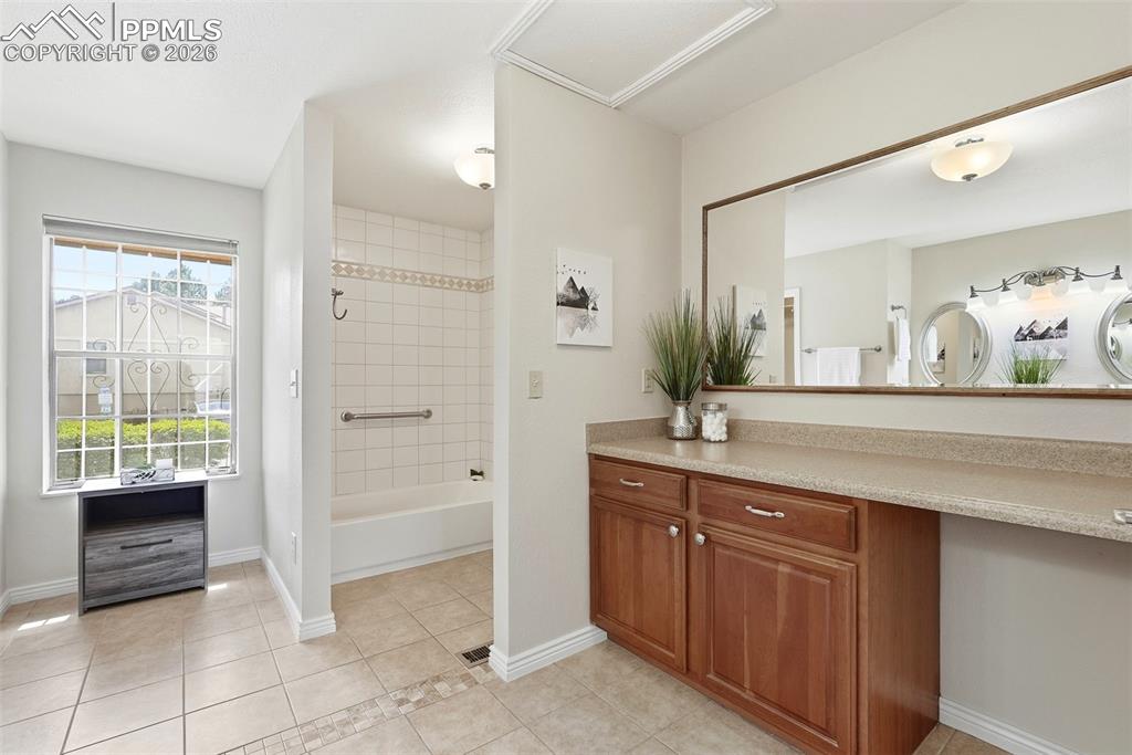 Image 20 of 44: This bathroom features a spacious vanity with wood cabinetry and a large mi