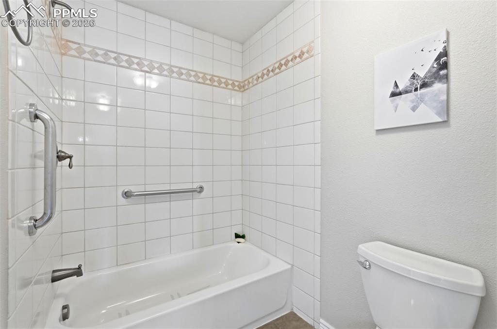 Image 21 of 44: Bathroom featuring a white tiled shower with an integrated bathtub, and a t