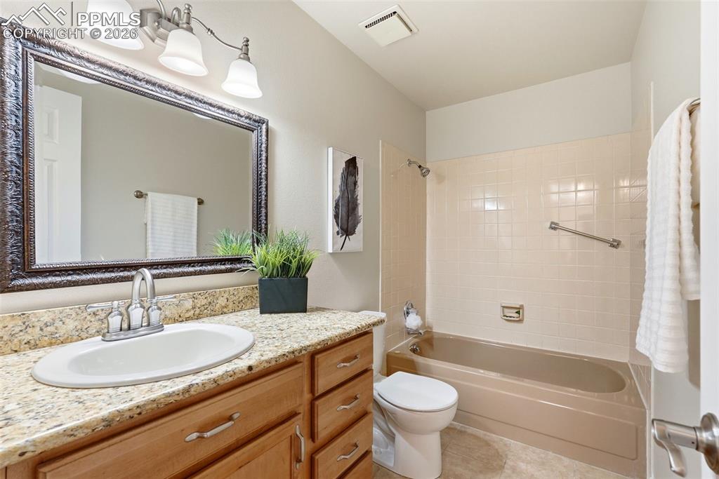 Image 23 of 44: Bathroom featuring a light-colored granite countertop, wood vanity with bru