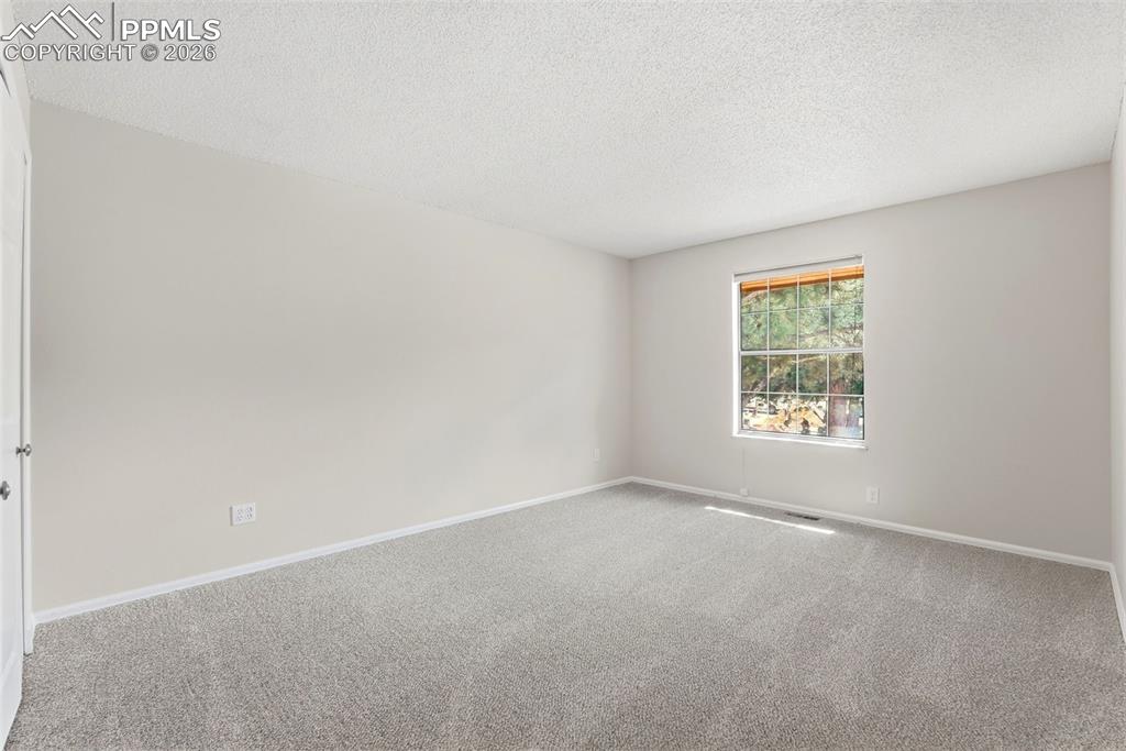 Image 24 of 44: The room features light gray carpet flooring, white walls, and a window pro