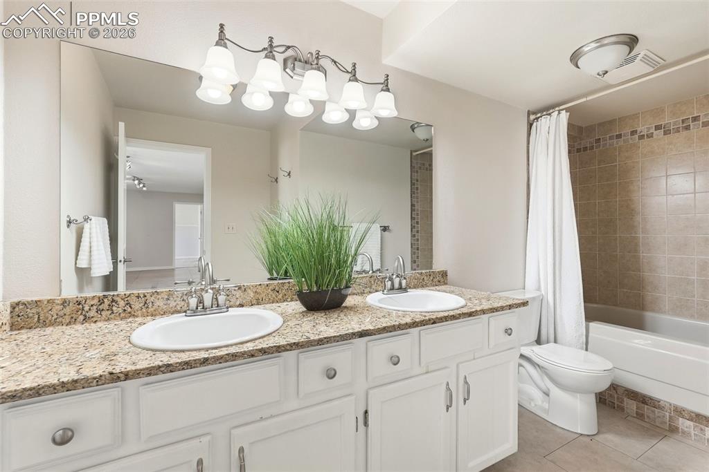 Image 30 of 44: The bathroom features a double vanity with a granite countertop and white c