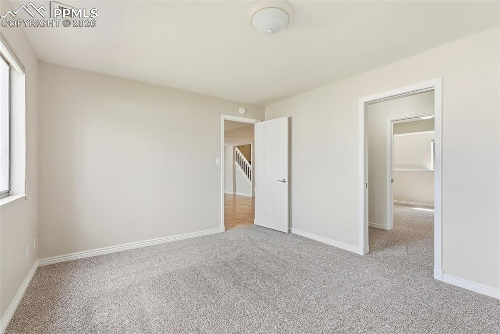 Image 32 of 44: This room features light gray carpeting, white trim, and a window providing