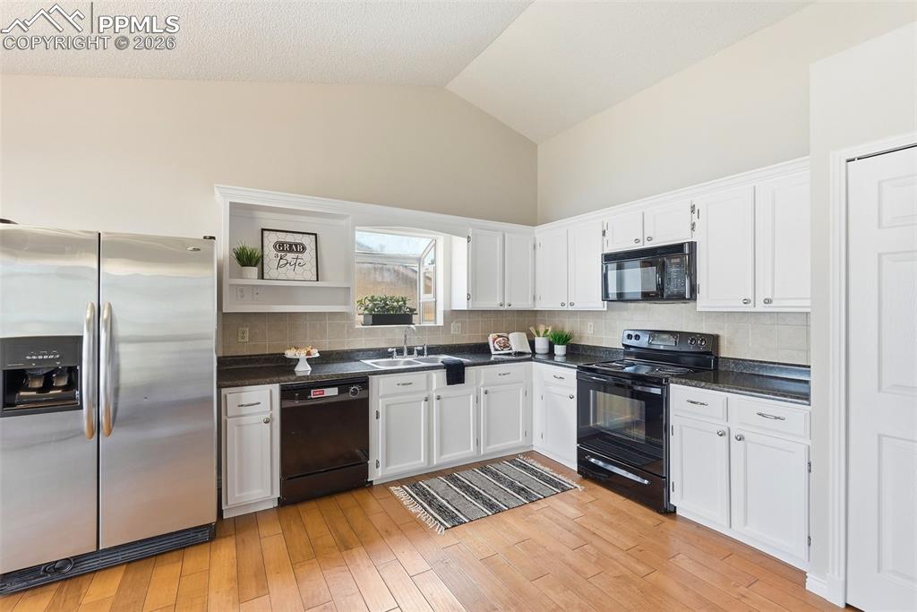 Image 4 of 44: Well-appointed kitchen featuring hardwood floors, white cabinetry, dark cou