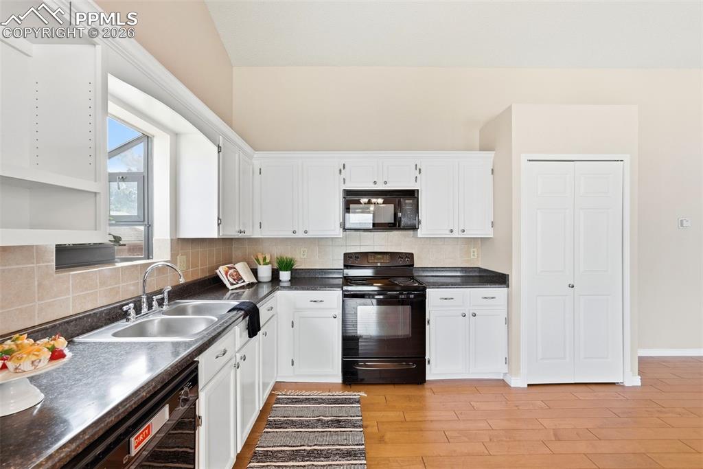 Image 5 of 44: The kitchen features white cabinetry, a double basin sink, black appliances
