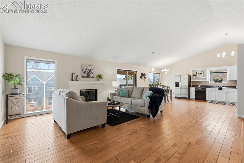 Image 7 of 44: The living area features hardwood floors, a white fireplace, and a large wi