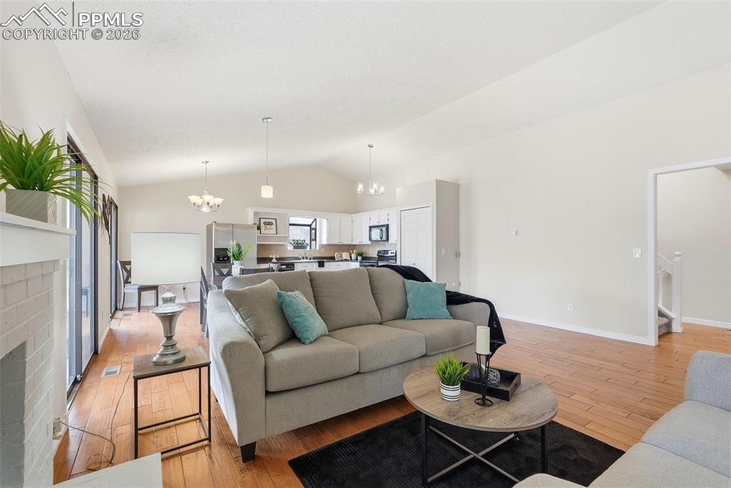 Image 8 of 44: Living area with vaulted ceilings, hardwood flooring, and sliding glass doo