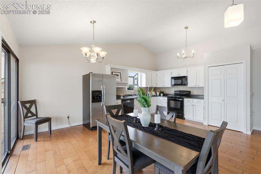 Image 9 of 44: Kitchen and dining area featuring hardwood floors, white cabinetry, a stain